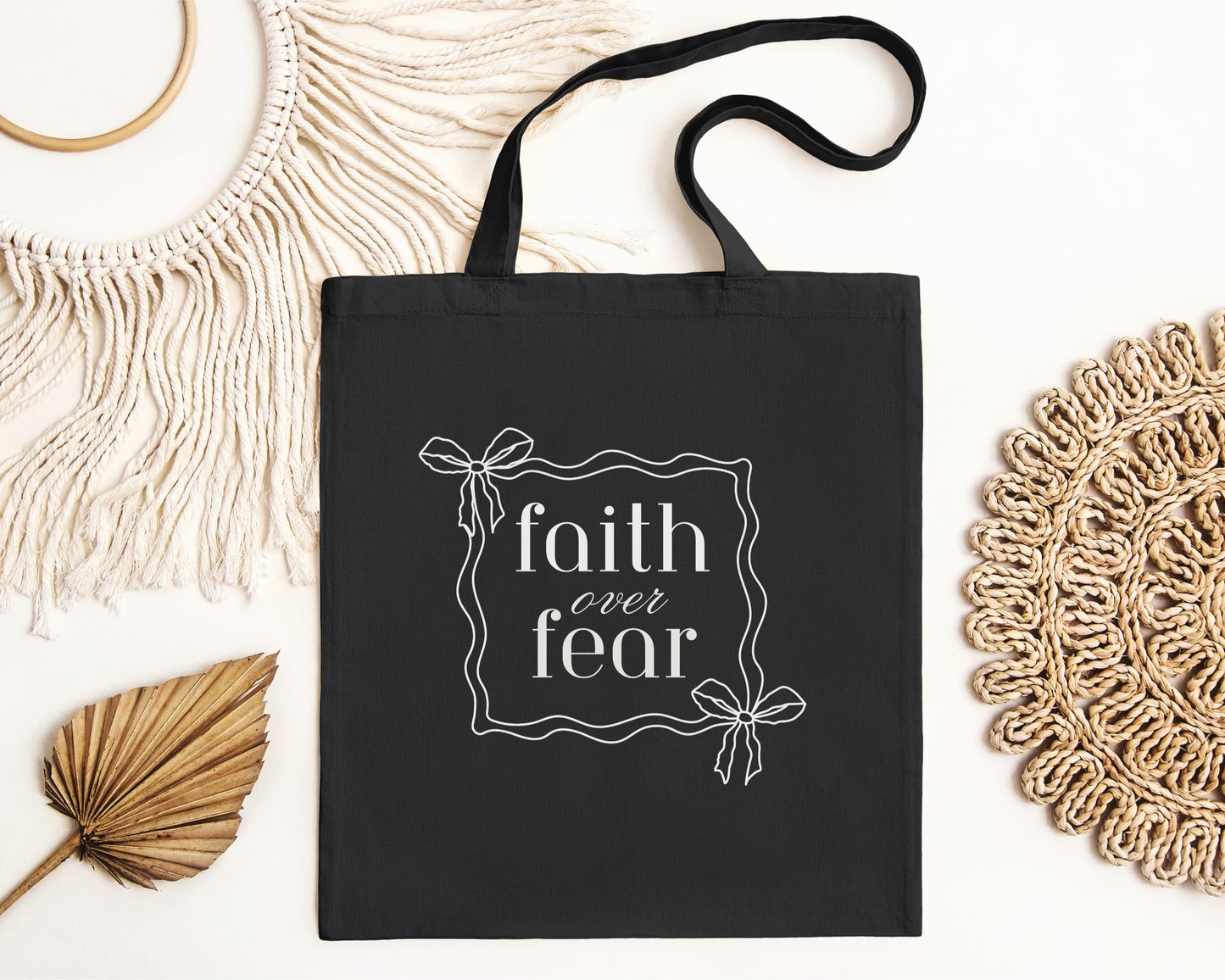 Christian tote bag with text "Faith Over Fear" and simple bow graphic. Cotton canvas bag for daily use.