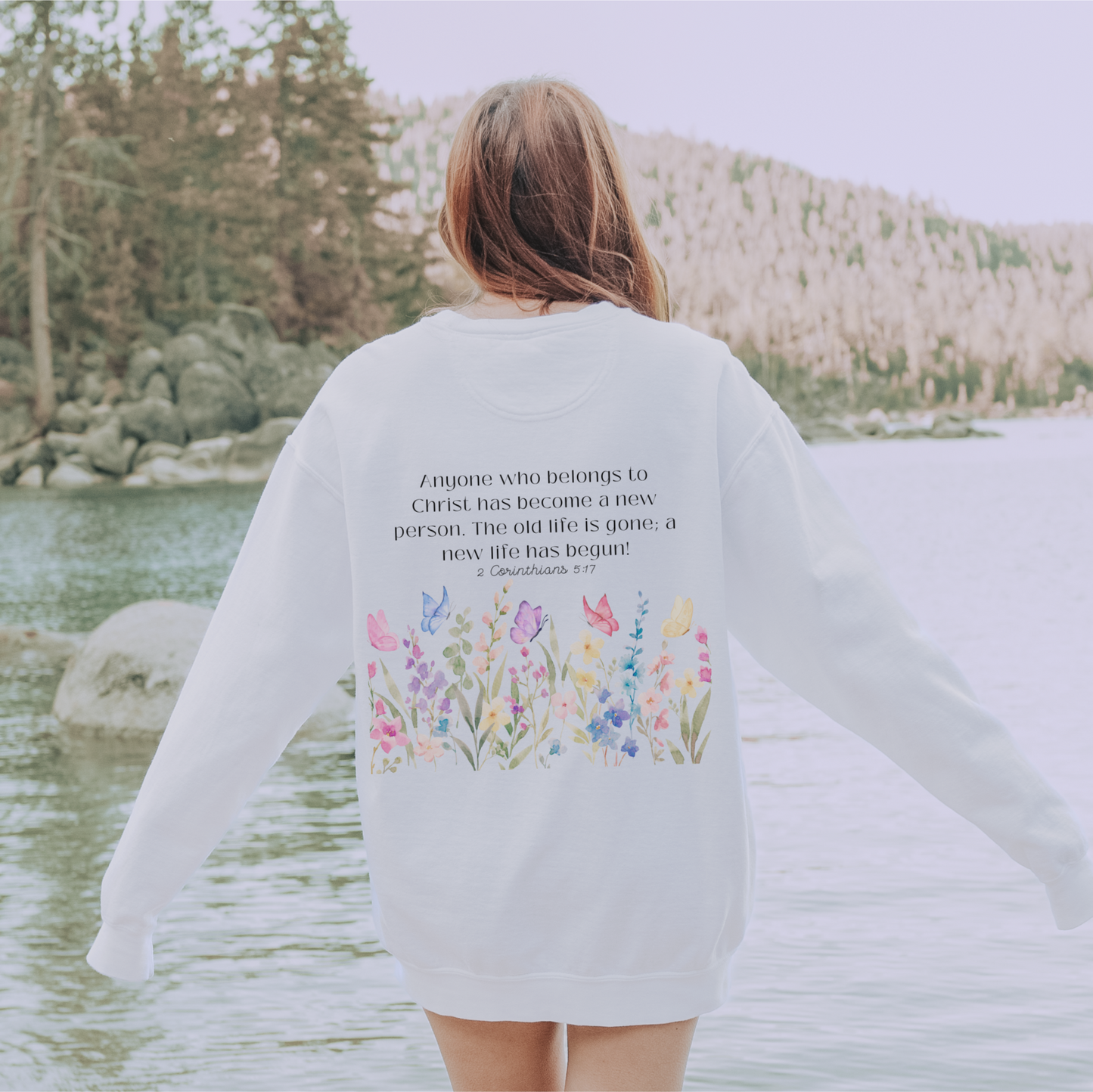 White faith-based sweatshirt with floral and butterfly design and scripture verse.