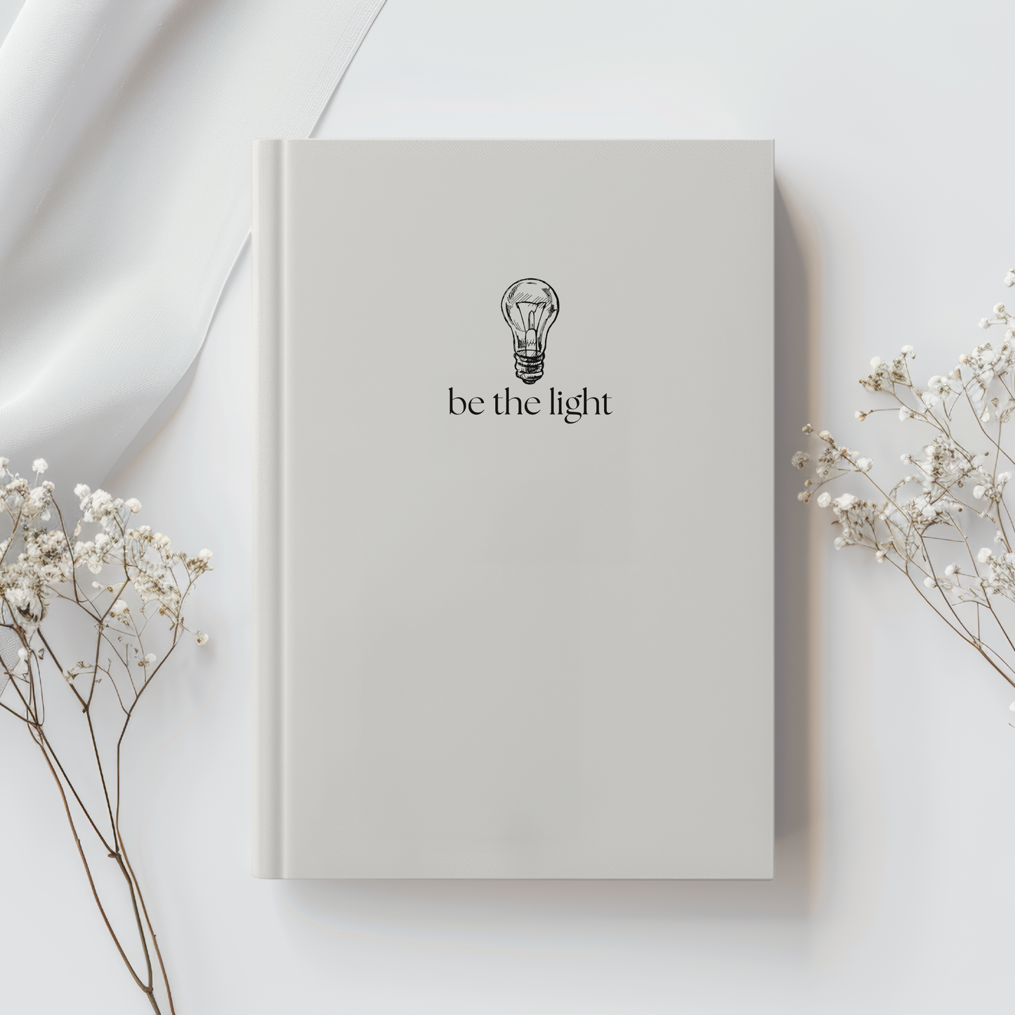 Neutral 5x7 Christian journal with lightbulb design and text "be the light," inspired by scripture verse Matthew 5:14. 