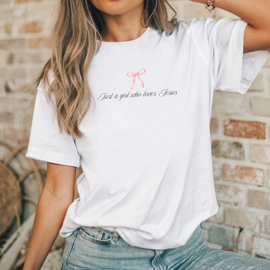 Christian t-shirt with the text 'Just a girl who loves Jesus' text with cute simple pink bow.  Faith based gift idea for women, teens or girls. 