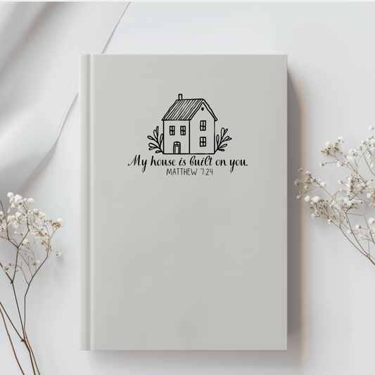 Christian prayer journal in cream neutral color. Simple house graphic with bible verse Matthew 7:24. 