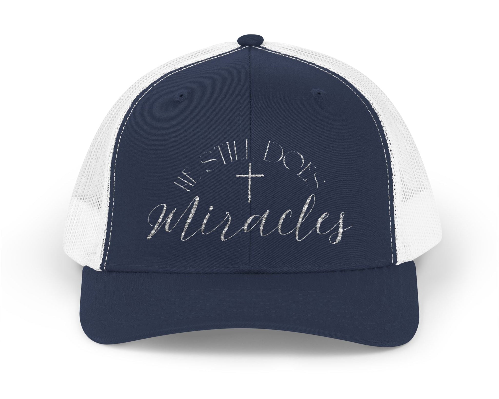 Religious trucker hat in navy and white  with white embroidery reading "He still does miracles". 